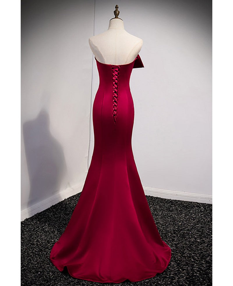 Un abito da ballo rosso vino nobile e minimalista, senza maniche, con spalle scoperte, spalline senza spalline e schiena color rosso vino e abito da sera a sirena lungo fino a terra.